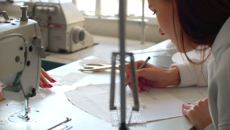 close-up-of-two-young-women-working-as-fashion-designers-and-drawing-sketches-for-clothes-in-atelier